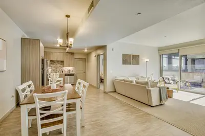a living room and dining room with a couch and a table at By Seaport Village and Navy Base! Chic Condo with Pool in National City