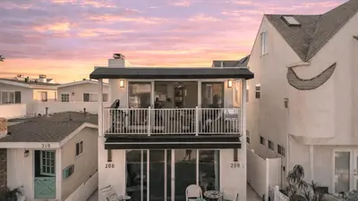 a house with a balcony with a sunset in the background at Seabright Sky by AvantStay Top-Floor West Newport Retreat • Balcony Near Beach Cafes in Newport Beach