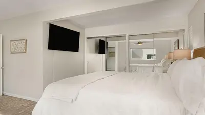 a white bedroom with a white bed and a tv at Seabright Sky by AvantStay Top-Floor West Newport Retreat • Balcony Near Beach Cafes in Newport Beach
