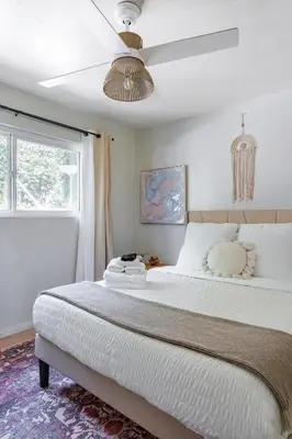 a bedroom with a large bed with a ceiling fan at Light & Airy by Coastline Vacation Rentals in San Diego