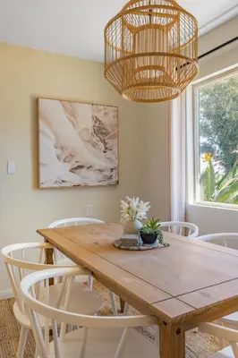 a dining room table with white chairs and a chandelier at Light & Airy by Coastline Vacation Rentals in San Diego