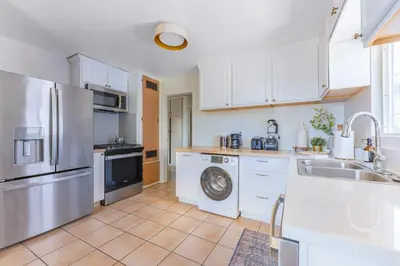 a kitchen with white cabinets and a washing machine at Light & Airy by Coastline Vacation Rentals in San Diego