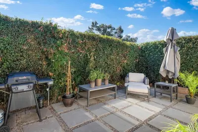 a patio with a grill and a chair and an umbrella at The Palm House by Coastline Vacation Rentals in San Diego