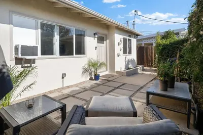 a patio with couches and tables in front of a house at The Palm House by Coastline Vacation Rentals in San Diego