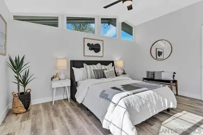 a white bedroom with a bed and a large window at Poolside Paradise in Central SD in San Diego