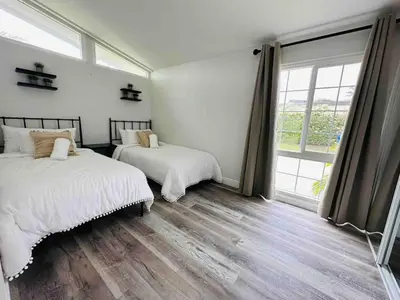 a bedroom with two beds and a large window at Poolside Paradise in Central SD in San Diego