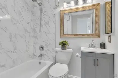 a bathroom with a toilet and a sink and a mirror at Poolside Paradise in Central SD in San Diego