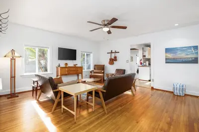 a living room with a ceiling fan and a table at Vintage Beach Bungalow in Oceanside