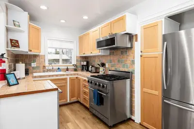 a kitchen with stainless steel appliances and wooden cabinets at Vintage Beach Bungalow in Oceanside