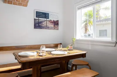 a dining room table with plates and glasses on it at Vintage Beach Bungalow in Oceanside