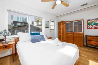 a bedroom with a large white bed with a ceiling fan at Vintage Beach Bungalow in Oceanside