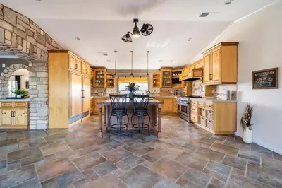 a kitchen with wooden cabinets and a table with chairs at Hilltop Wine Estate- Pickleball - Pool - 360 views in Temecula