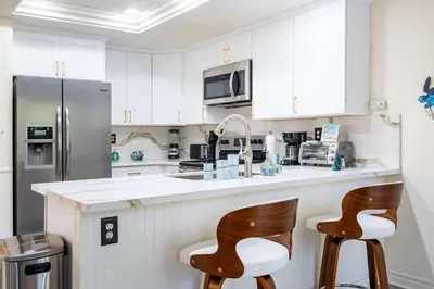 a kitchen with white cabinets and two bar stools at Luxe 2-Story Oasis with Private Pool & Backyard in Laguna Niguel