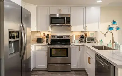 a kitchen with white cabinets and a stainless steel refrigerator at Luxe 2-Story Oasis with Private Pool & Backyard in Laguna Niguel