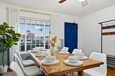 a dining room with a wooden table and white chairs at 4BR Family Retreat with Hot Tub Games & Fire Pit in Chula Vista