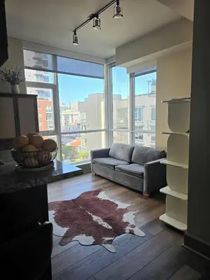 a living room with a couch and a large window at Downtown Beautiful 3-bedroom Apartment Steps to Convention Center, Petco Park! in San Diego