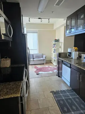 a kitchen with black cabinets and a living room at Downtown Beautiful 3-bedroom Apartment Steps to Convention Center, Petco Park! in San Diego