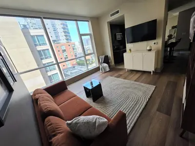 a living room with a couch and a large window at Downtown Beautiful 3-bedroom Apartment Steps to Convention Center, Petco Park! in San Diego