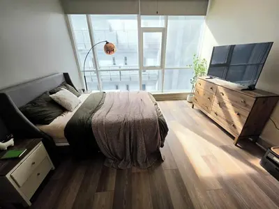 a bedroom with a bed and a dresser and a large window at Downtown Beautiful 3-bedroom Apartment Steps to Convention Center, Petco Park! in San Diego