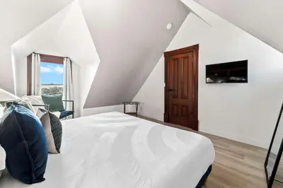 a white bedroom with a bed and a tv at Top 2 Floors Historic Mansion Game Room City Views in San Diego