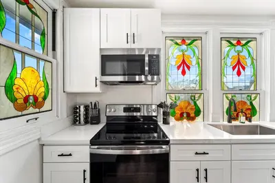 a kitchen with white cabinets with stained glass windows at Top 2 Floors Historic Mansion Game Room City Views in San Diego