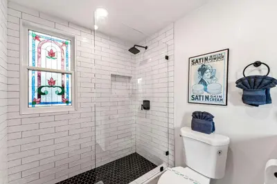 a white bathroom with a window and a toilet at Iconic Mansion with Hot Tub GYM Arcade and Parking in San Diego