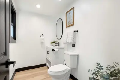 a white bathroom with a toilet and a mirror at Iconic Mansion with Hot Tub GYM Arcade and Parking in San Diego