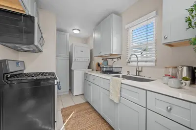 a kitchen with white cabinets and a black refrigerator at Stylish 1BR Home with Parking Near Zoo & Downtown in San Diego