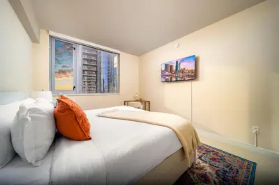 a bedroom with a bed with an orange pillow and two windows at Electra Building 2bed - Views Pool Sauna Spa in San Diego