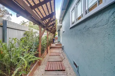 a walkway with a blue building with a wooden pergola at Casa Mellifora 3BR Golden Hill w Garage Parking in San Diego