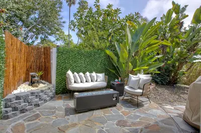 a patio with two chairs and a couch and a tv at O-side Oasis in Oceanside