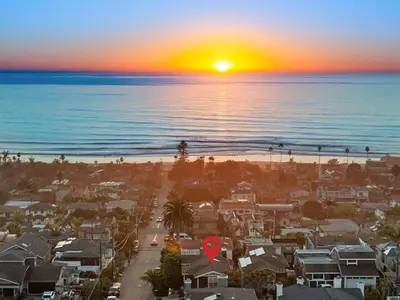 a sunset over a beach with houses and the ocean at Golden Hour by Coastline Vacation Rentals in Encinitas