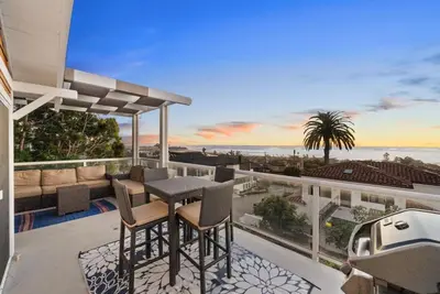 a balcony with a table and chairs and the ocean at Golden Hour by Coastline Vacation Rentals in Encinitas