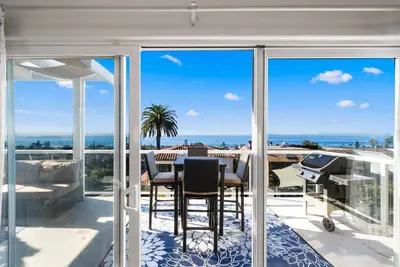 a patio with a table and chairs and a view of the ocean at Golden Hour by Coastline Vacation Rentals in Encinitas