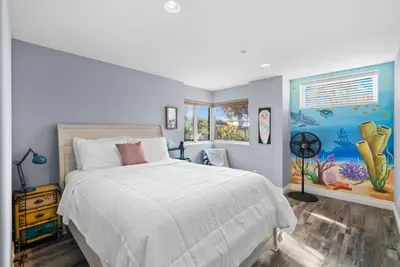a bedroom with a bed and a painting on the wall at Golden Hour by Coastline Vacation Rentals in Encinitas