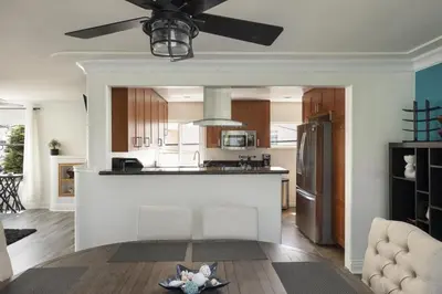 a living room with a kitchen with a ceiling fan at Blue Tide by Coastline Vacation Rentals in San Diego
