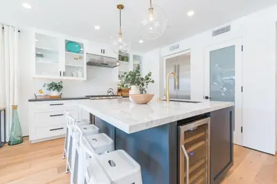a kitchen with white cabinets and a blue island with stools at 6Br Tri-Level W Ac, Ocean Views, Rooftop Deck And Hot Tub By Beachview Rentals in Newport Beach