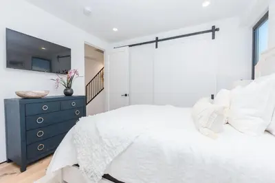 a bedroom with a white bed and a blue dresser at 6Br Tri-Level W Ac, Ocean Views, Rooftop Deck And Hot Tub By Beachview Rentals in Newport Beach