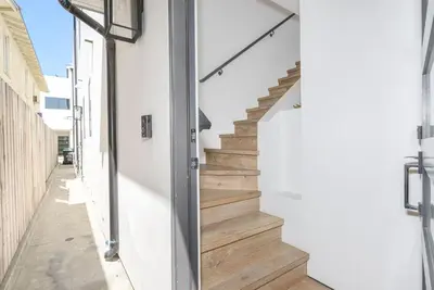 a stairwell in a house with white walls and wooden floors at 6Br Tri-Level W Ac, Ocean Views, Rooftop Deck And Hot Tub By Beachview Rentals in Newport Beach