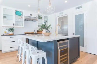 a kitchen with white cabinets and a blue island with stools at 6Br Tri-Level W Ac, Ocean Views, Rooftop Deck And Hot Tub By Beachview Rentals in Newport Beach