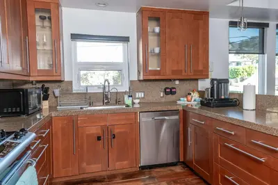 a kitchen with wooden cabinets and a stainless steel dishwasher at Chic Downtown SD Hub for Families & Friends in San Diego