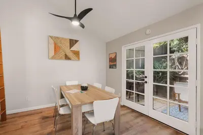 a dining room with a wooden table and white chairs at The Artist's Loft by Coastline Vacation Rentals in San Diego