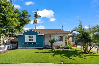 a blue house with palm trees in a yard at The Mosaic by Coastline Vacation Rentals in San Diego