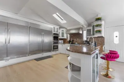 a kitchen with stainless steel appliances and pink stools at Family Pool House Oasis in National City