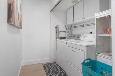 a kitchen with white cabinets and a washer and dryer at Family Pool House Oasis in National City