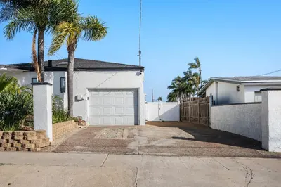 a white house with a garage and palm trees at Family Pool House Oasis in National City
