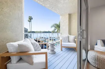 a balcony with white furniture and a view of the ocean at Marina Dream - Lagoon Views in Carlsbad