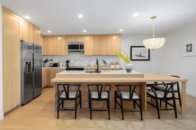 a kitchen with a large wooden table with bar stools at Marina Dream - Lagoon Views in Carlsbad