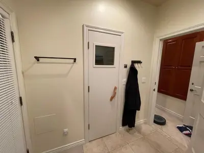 a hallway with a door and a coat on a rack at San Diego French Garden Poolside Retreat - Wine Country & Safari Park in Escondido