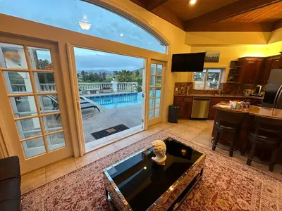 a living room with a large window and a pool at San Diego French Garden Poolside Retreat - Wine Country & Safari Park in Escondido